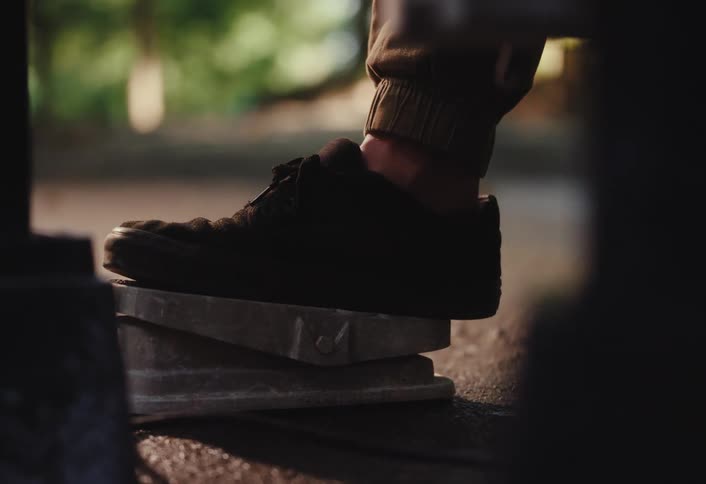 A person's foot in a black shoe presses down on a pedal in slow motion