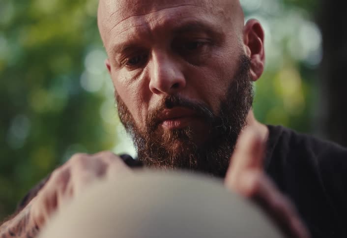Close-up of a focused bald man with a beard concentrating intently on his craft outdoors