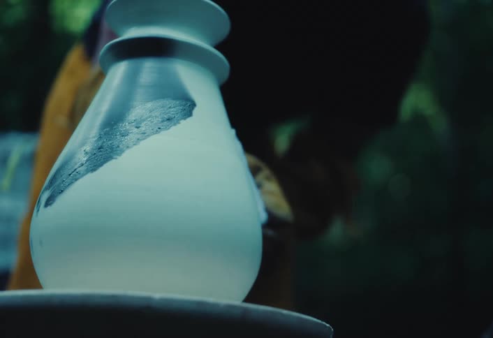 A ceramic artist delicately paints a unique design onto a handmade pottery vase in a tranquil outdoor studio