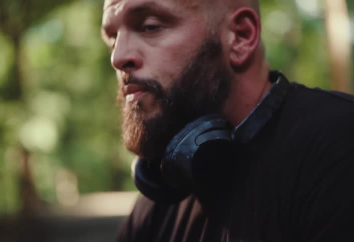 Focus shifts from a clay pot on a potter's wheel to the intense close-up portrait of a bald, bearded man