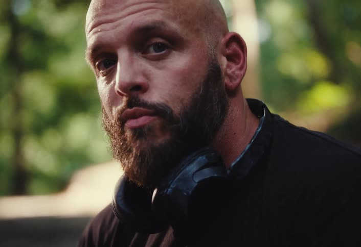 A rack focus shot transitions from a spinning clay pot to the intense face of a bearded potter looking seriously at the camera