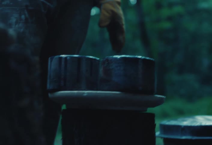 Slow motion close-up of two freshly fired handmade ceramic bowls steaming as they cool in a dark, moody forest workshop