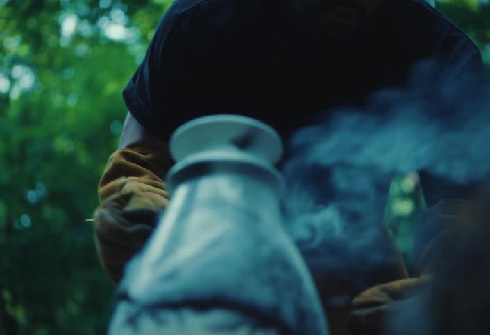 Close-up of a potter holding a smoldering Raku-fired vase as smoke reveals its intricate crackled design