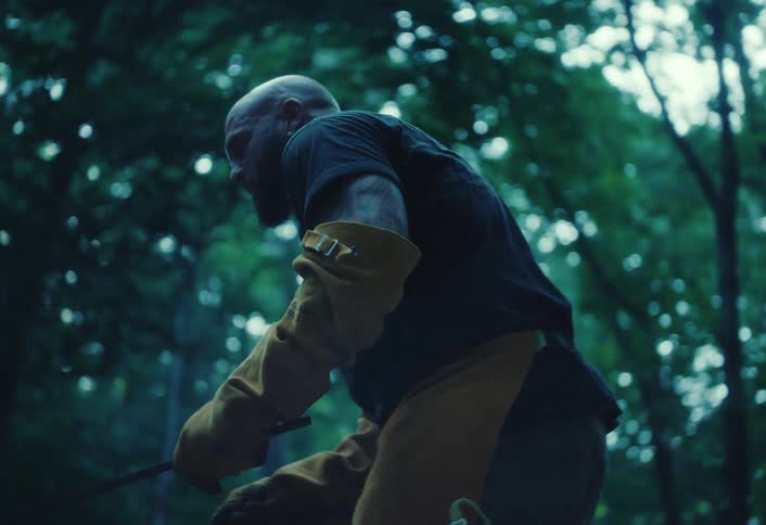 A potter wearing protective gear carefully removes a freshly fired ceramic vase with tongs in a slow-motion, rack focus shot
