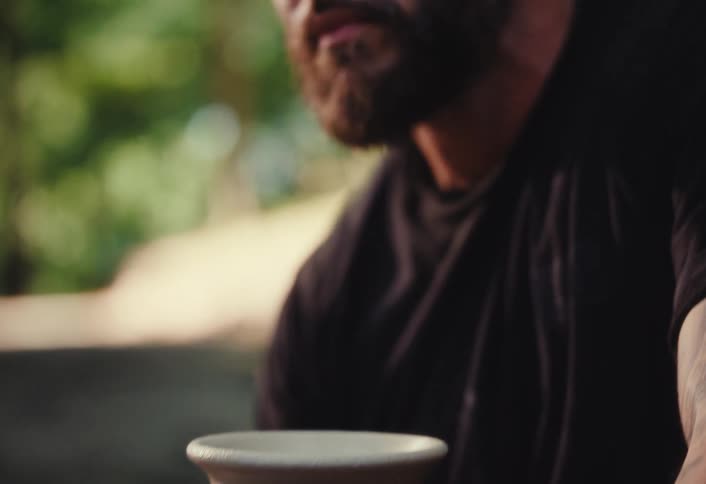 A slow reveal shot pans from a spinning clay pot up to the intense and focused face of the male potter