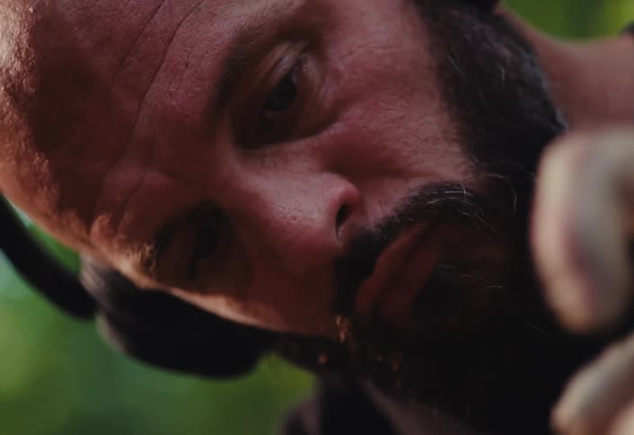 A close-up shot of a focused, bearded potter carefully shaping clay on his wheel