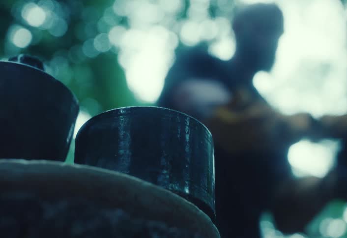 Mysterious blurred silhouette of an artisan working behind finished ceramic pots in a moody, cool-toned outdoor setting