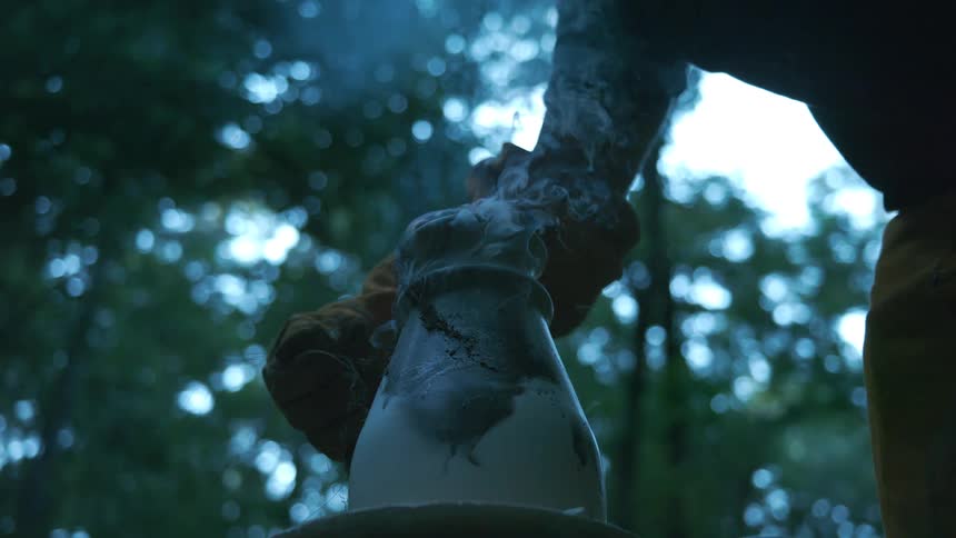 Slow motion low angle shot of a freshly fired ceramic pot smoking in the hands of a potter wearing protective gloves