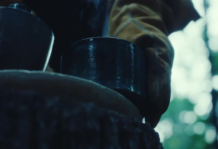 A potter in protective gloves carefully pours water over a hot, freshly fired ceramic cup, causing it to steam dramatically in slow motion