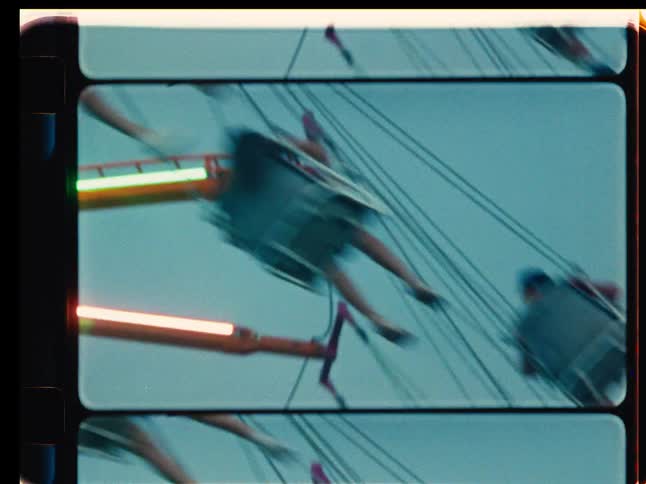 Vintage Super 8 film captures a motion-blurred, high-speed view of a spinning swing ride at a carnival