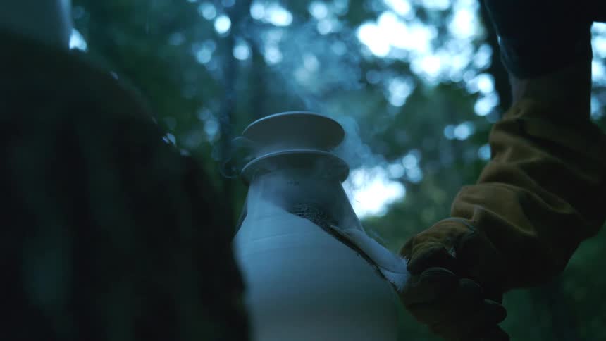 A gloved hand carefully applies a feather to a steaming hot ceramic vase, creating patterns in the glaze in slow motion