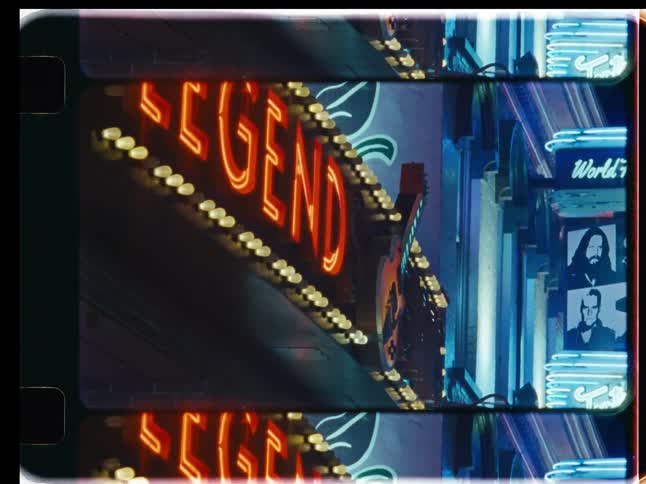 A vertical shot of a vintage film strip shows a bright red and yellow neon sign spelling 'LEGEND' on a city street at night