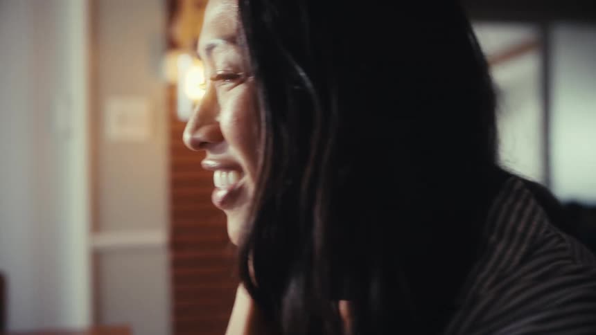 A slow-motion close-up of a woman's emotional transformation from sadness to pure joy and laughter