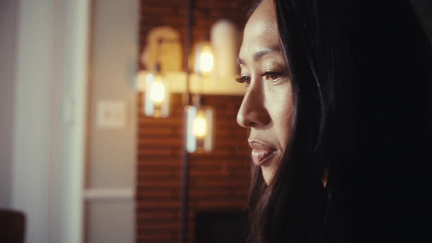 A woman works from home on her laptop at the dining table, with the camera slowly zooming in on her focused expression