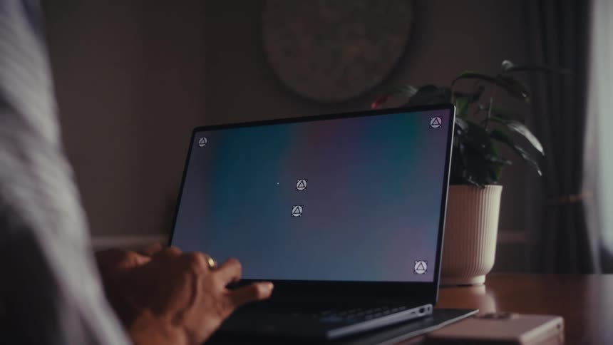 Over the shoulder shot of a person using a laptop with a screen ready for compositing in a home office