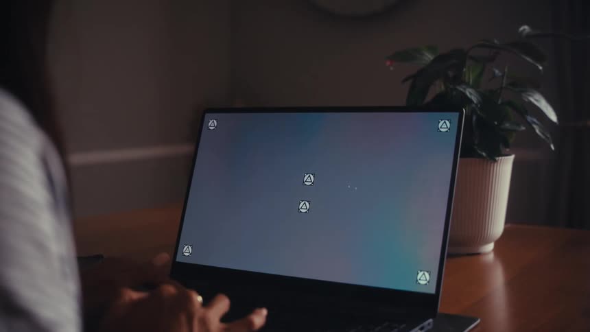 Over the shoulder shot of a person typing on a laptop with a screen ready for compositing in a dimly lit room