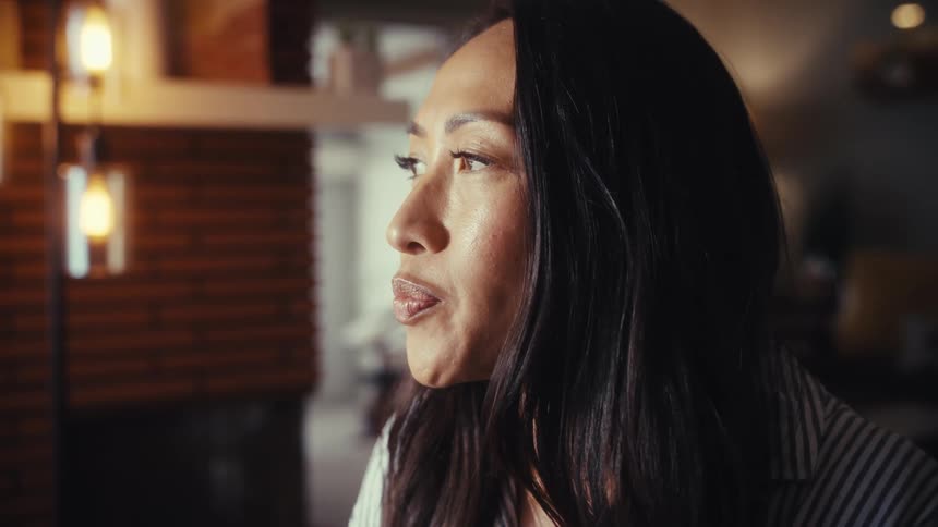 An intimate close-up shows an Asian woman's expression shifting from a smile to a thoughtful look as she engages in a conversation