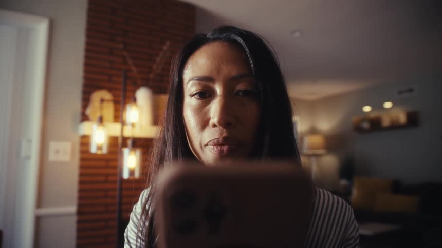 A woman is captivated by her smartphone screen while relaxing in her cozy, stylish living room