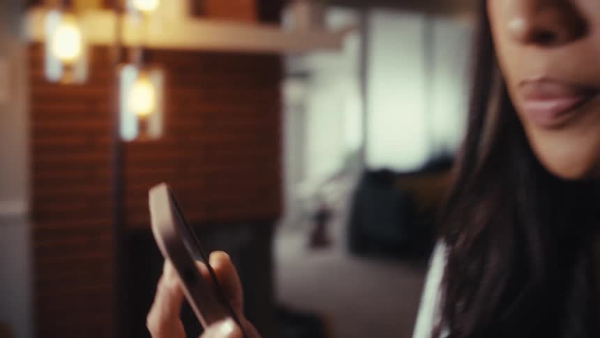 A woman working on her laptop at her dining room table stops to take a phone call in slow motion