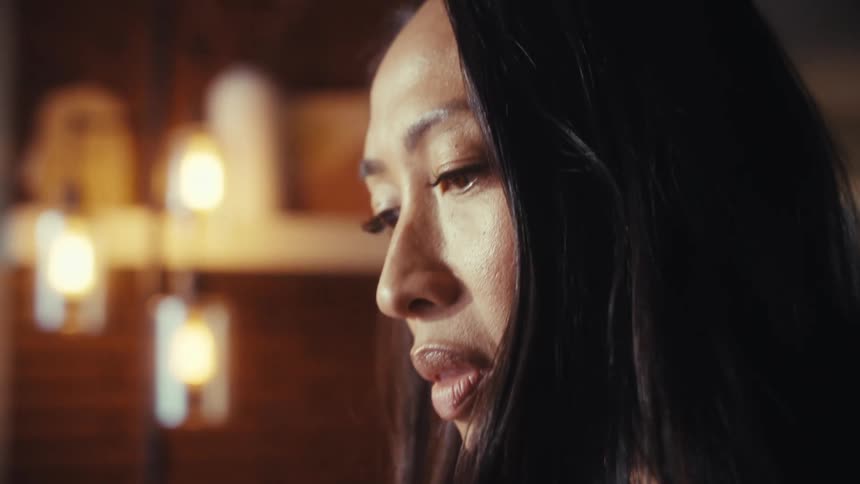 A slow-motion close-up of a focused woman typing on her laptop, with the camera panning from her hands to her face