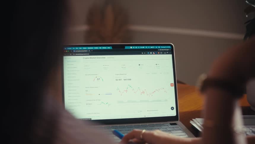 An over-the-shoulder view of two people analyzing cryptocurrency market data on a laptop screen
