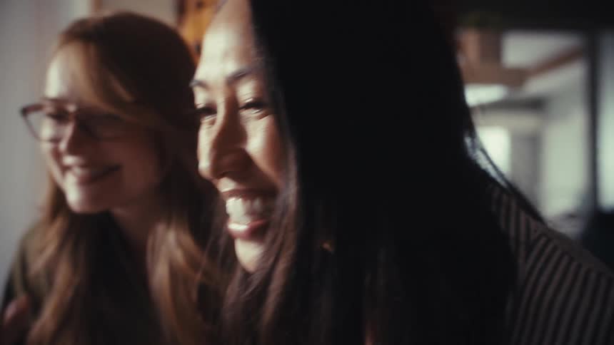 Two excited diverse female friends laugh and celebrate together in slow motion