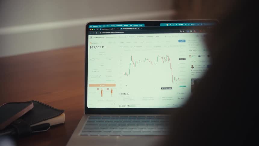 A man and woman collaborate while analyzing financial market trends on a laptop computer