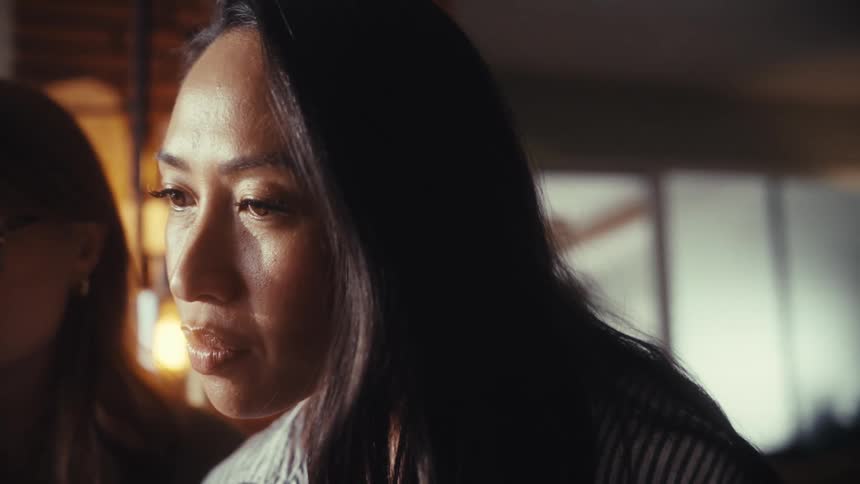 A slow-motion close-up captures two diverse businesswomen in a serious discussion that ends with a smile