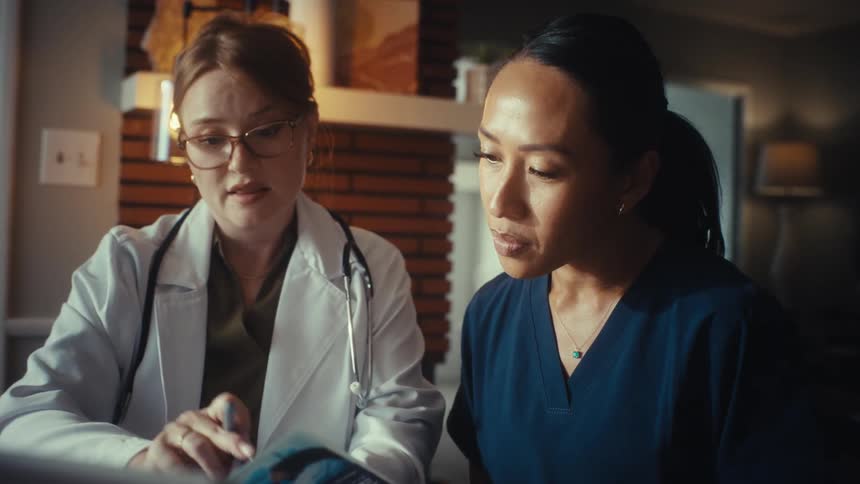 A female doctor and nurse collaborate and discuss a patient's case while reviewing a medical brochure together