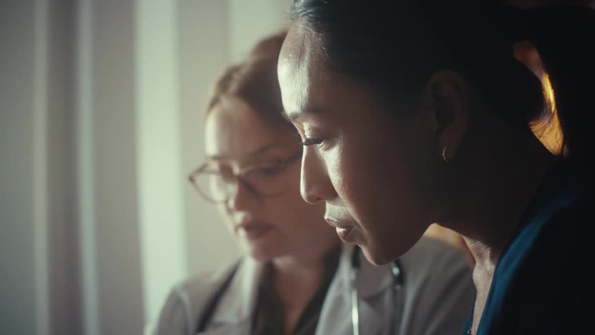 Two diverse female doctors intently review and discuss important medical information together in an office