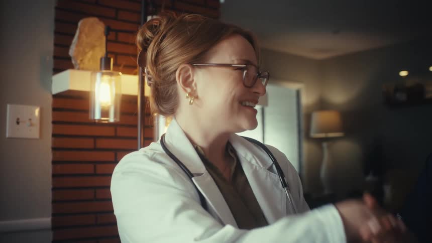 A female doctor and nurse collaborate while reviewing information on a tablet, concluding their meeting with a friendly handshake in an office