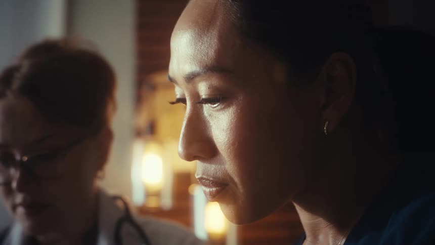 Intense close-up of a focused nurse collaborating with a doctor during a late-night hospital shift