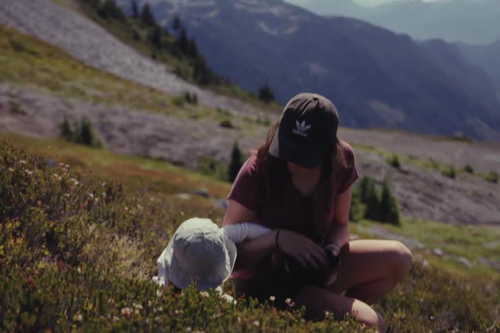 A mother and her young child forage for wild berries together in a beautiful alpine meadow on a sunny day