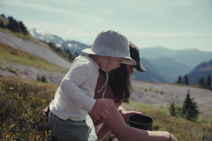 A mother and her young child pick fresh wild berries together on a beautiful sunny day in the mountains