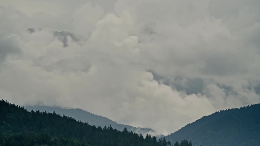 A dramatic timelapse of thick, heavy clouds swirling and engulfing a majestic mountain range