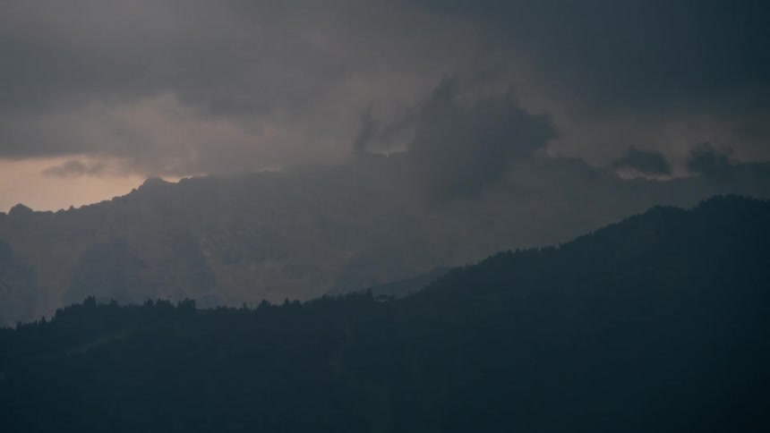 A time-lapse of a dark and moody mountain range as a storm rolls in at dusk