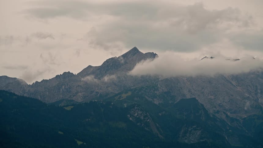 Dramatic timelapse of clouds moving over a majestic mountain range on a moody, overcast day
