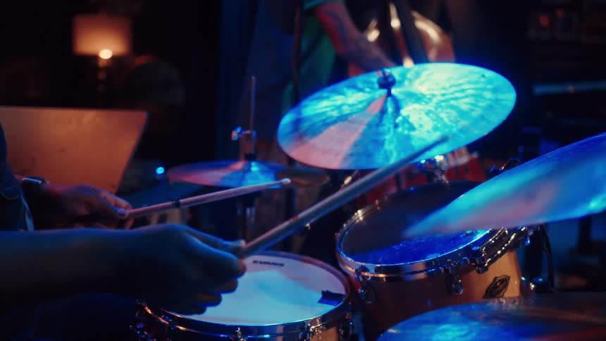 A drummer plays the cymbals in a blue-lit studio during a recording session in slow motion