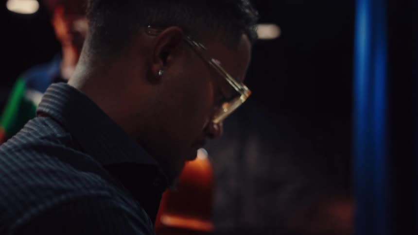 A stylish African American musician passionately plays a beautiful melody on a grand piano in a dimly lit studio