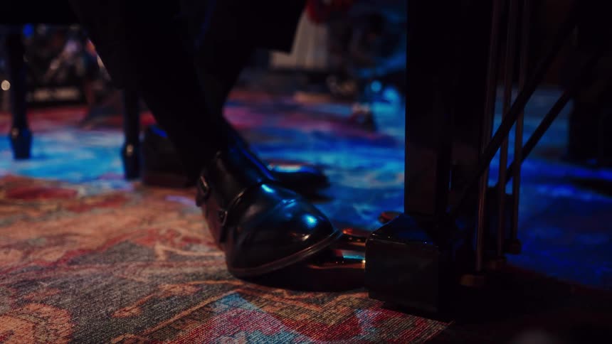 A pianist in elegant black shoes expertly manipulates the golden pedals of a grand piano during a performance