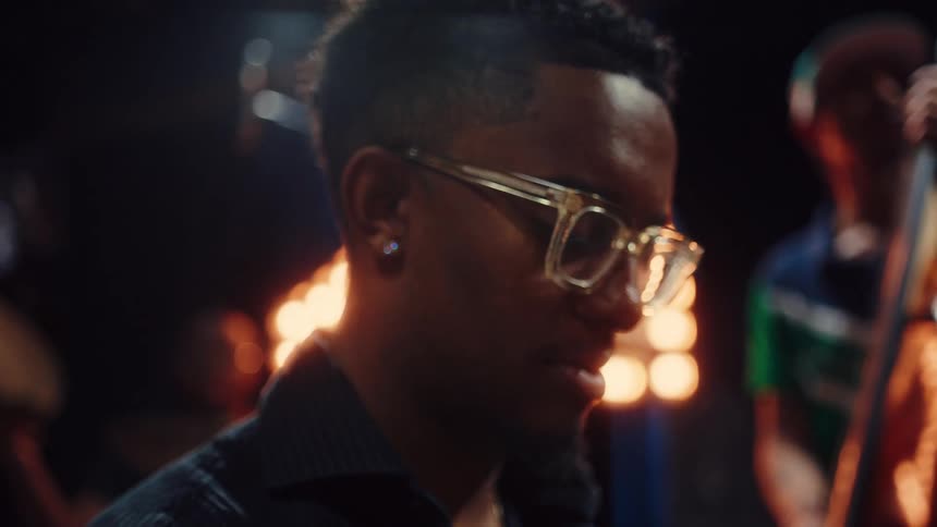 A close-up shot transitions from the strings of a grand piano to a smiling musician playing soulfully with his jazz band in a warmly lit studio