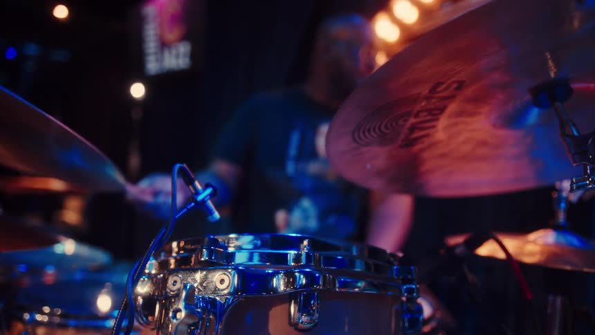 A drummer performs a passionate solo on his drum kit during a live set at a dimly lit jazz club