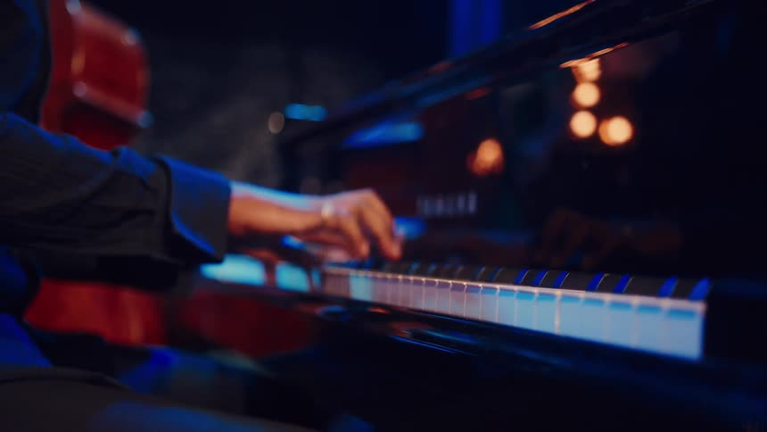 Close-up of a jazz musician's hands gracefully playing a soulful melody on a grand piano in a dimly lit club