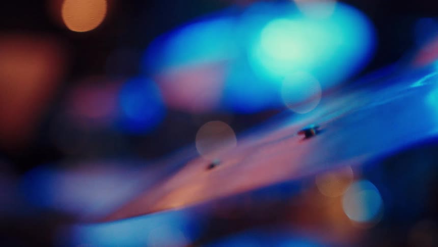 An artistic close-up captures a drum cymbal vibrating in slow motion under dramatic blue and orange stage lighting