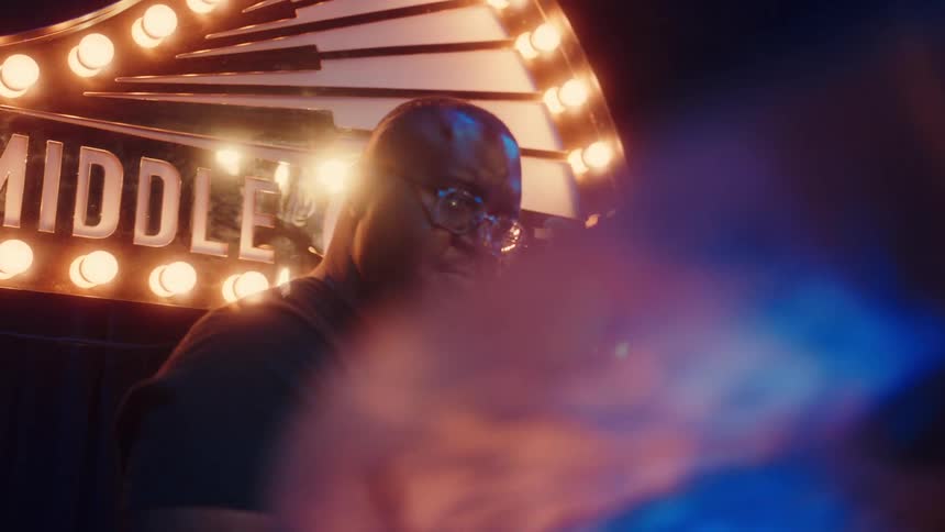 A passionate African American drummer plays a smooth rhythm on his drum kit during a live jazz performance in a dimly lit club