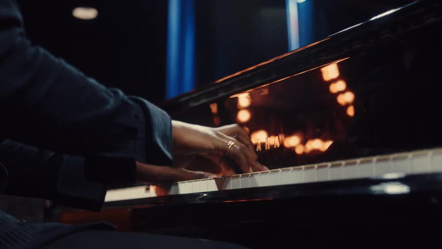 A soulful musician passionately plays a Yamaha grand piano under dramatic spotlights in a dark studio