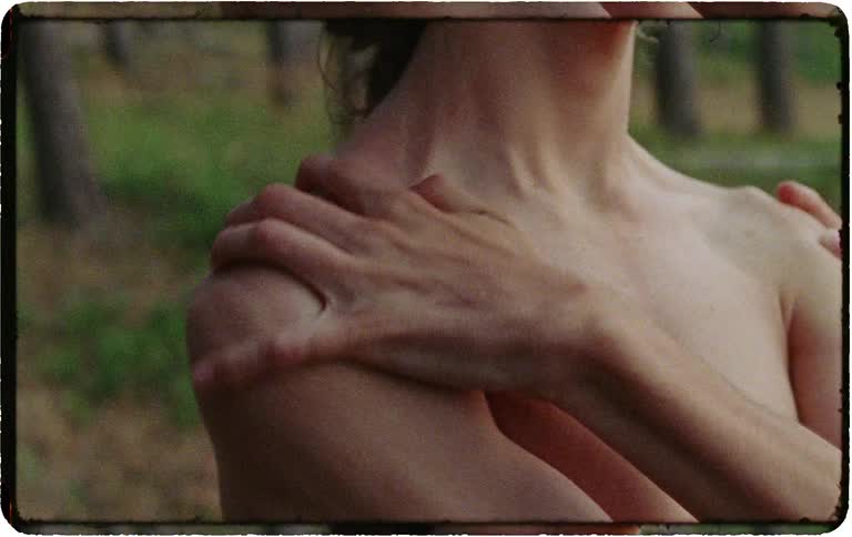 A vintage, film-style close-up of a young person being gently embraced by another's hands in a natural outdoor setting