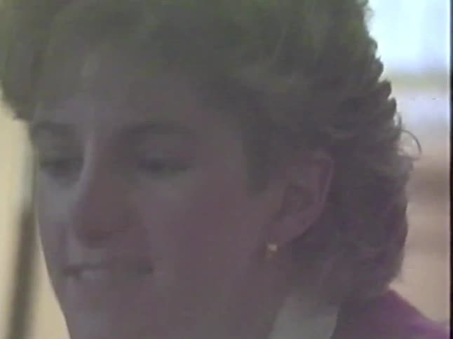 A candid close-up from vintage 1980s VHS footage shows a smiling young woman with blonde hair during a conversation
