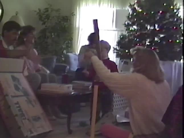 Vintage VHS footage shows a family gathered in the living room on Christmas morning as a young boy gets a toy baseball set