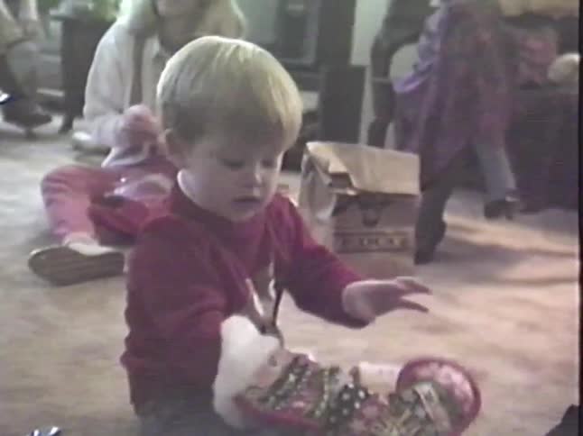 A nostalgic home movie from the 1980s shows a young boy curiously exploring the contents of his Christmas stocking